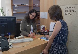 Person beim Ausleihen eines Buches