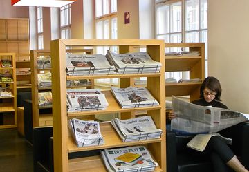 Eine Person liest in der Leselounge eine Zeitung
