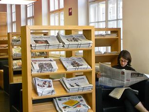 Eine Person liest in der Leselounge eine Zeitung