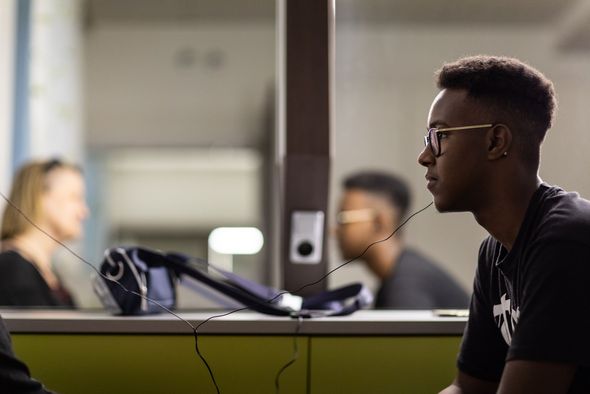 Junger Mann sitzt gegenüber einer Frau und teil mit ihr seine Kopfhörer.