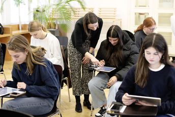 Schülerinnen arbeiten mit Tablets. Vortragende unterstützt eine Schülerin.