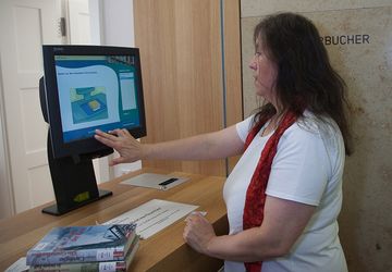 Person beim Ausleihen von Büchern an einer Selbstverbucherstation